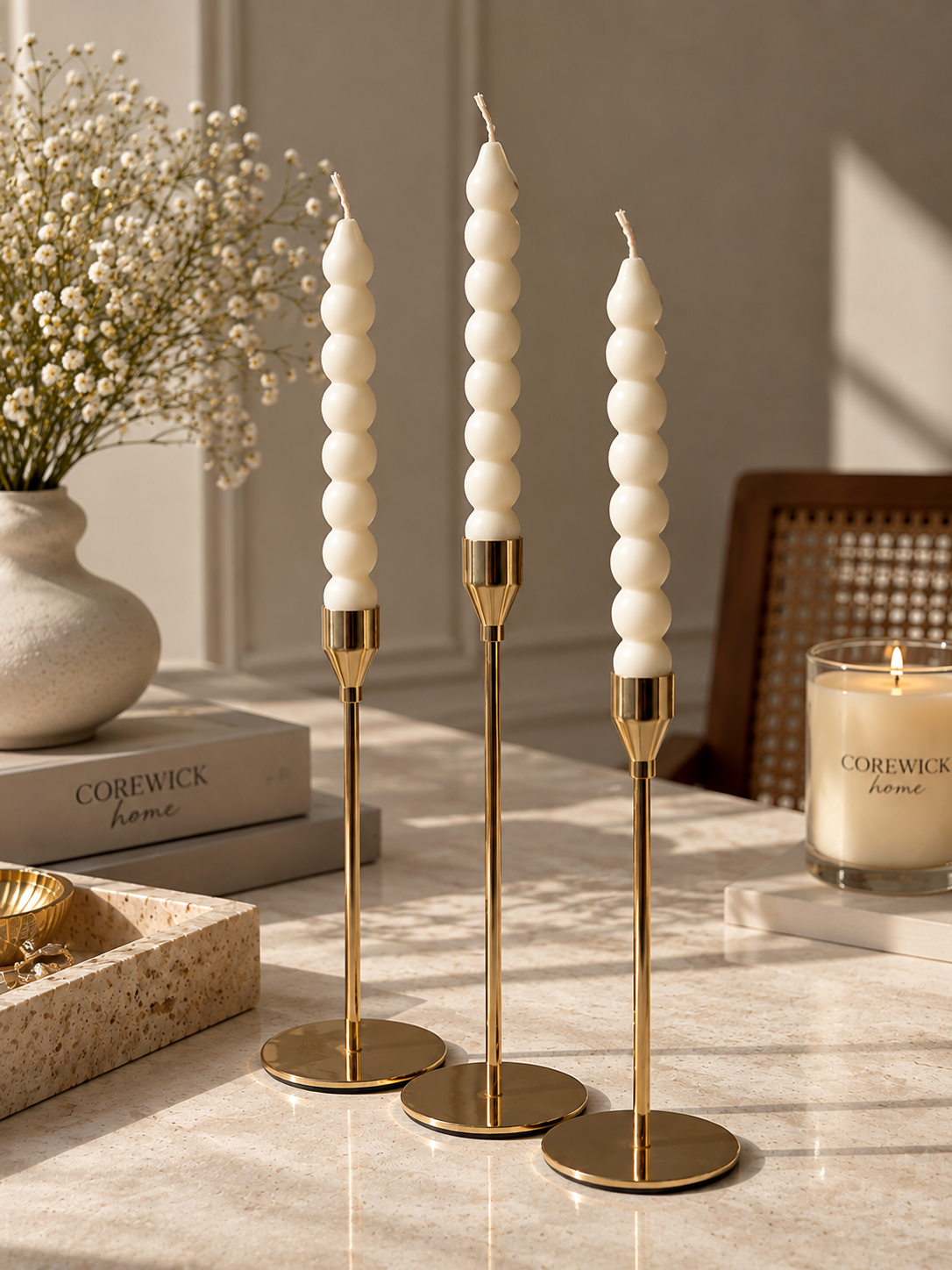 Gold candlestick set with bubble taper candles and CoreWick candle on marble