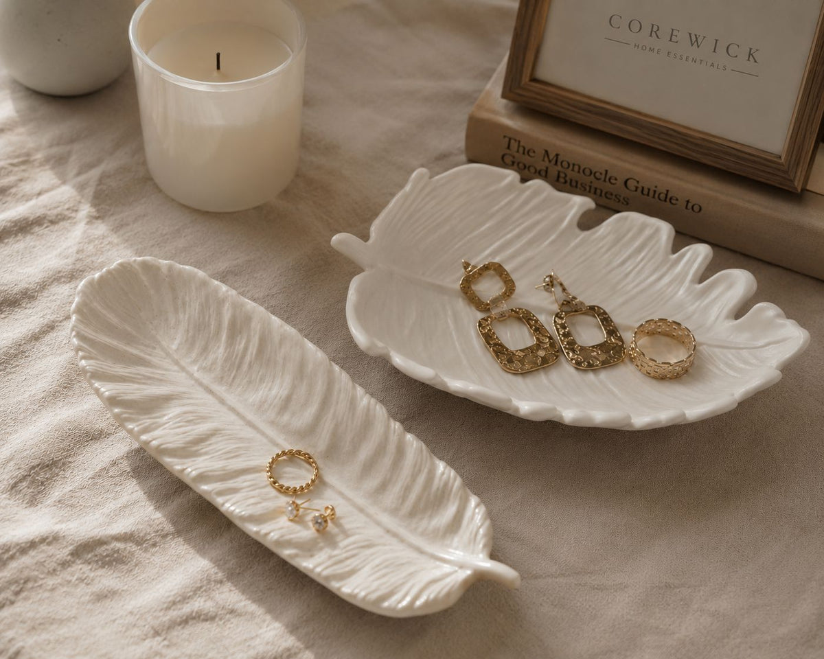 Leaf tray duo — feather and tropical leaf shaped white trays styled with gold jewellery and CoreWick candle