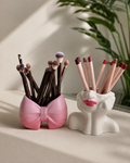 The Rosy Duo — pink bow brush holder and white lady face brush holder side by side