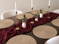 Natural jute round placemats styled on a dark dining table with a burgundy linen runner and brass candlesticks