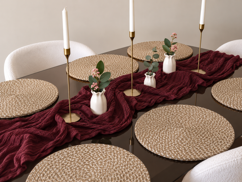 Natural jute round placemats styled on a dark dining table with a burgundy linen runner and brass candlesticks