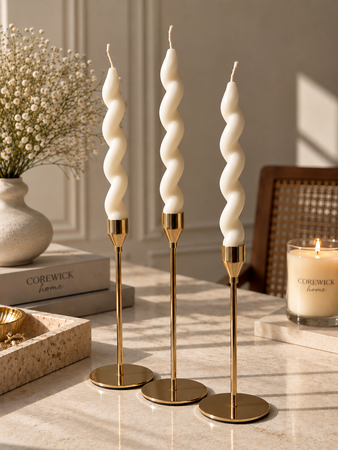 Gold candlestick set with spiral twist taper candles on marble surface